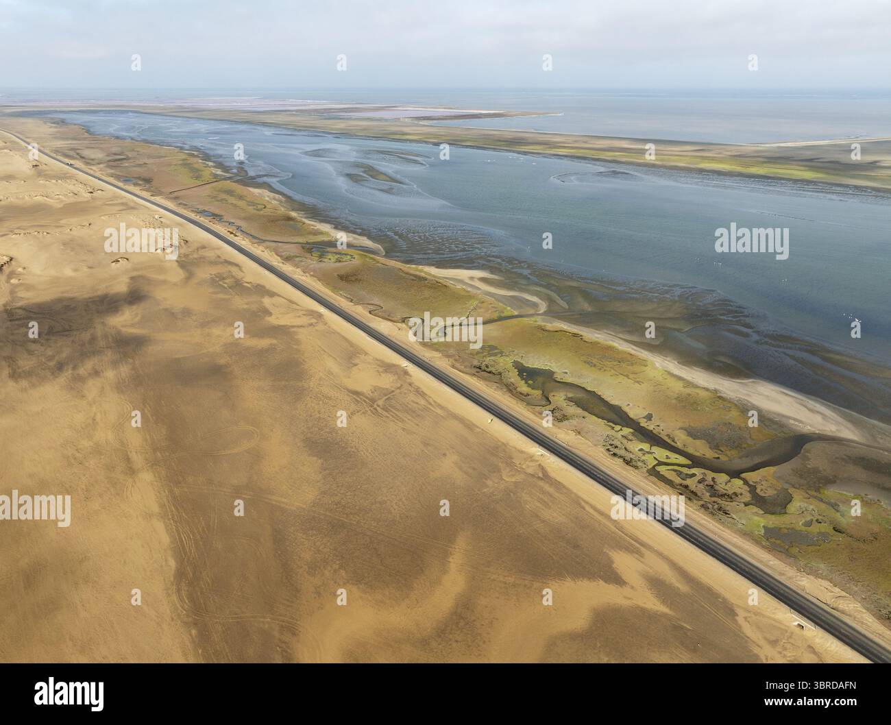 Vue aérienne d'une route droite coupe le paysage aride le long de la rivière saumâtre menant à la mer, Windhoek, région de Khomas, Namibie. Banque D'Images