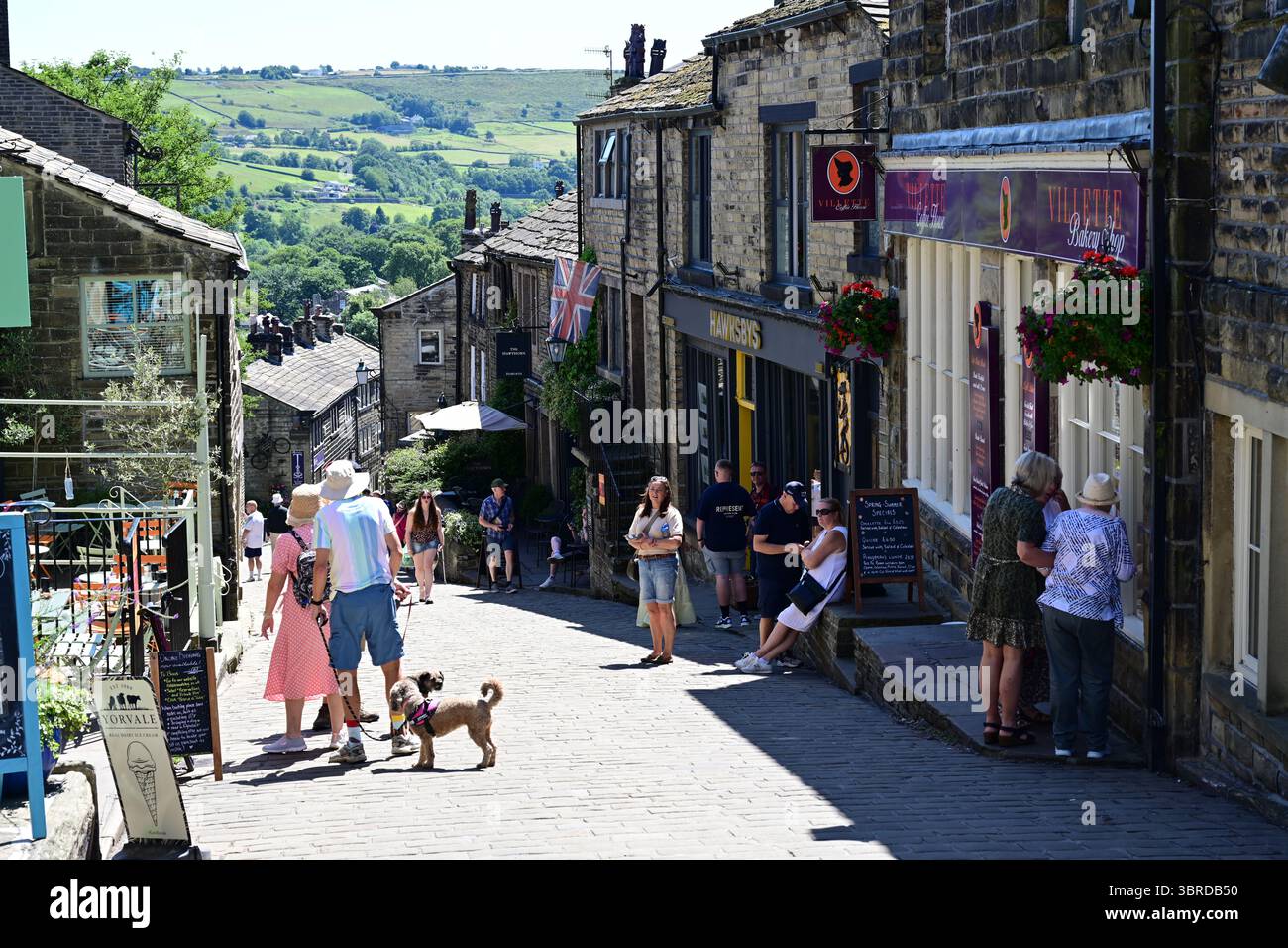 Shoppers sur Haworth main Street, soleil d'été, Bronte Country, West Yorkshire. Banque D'Images