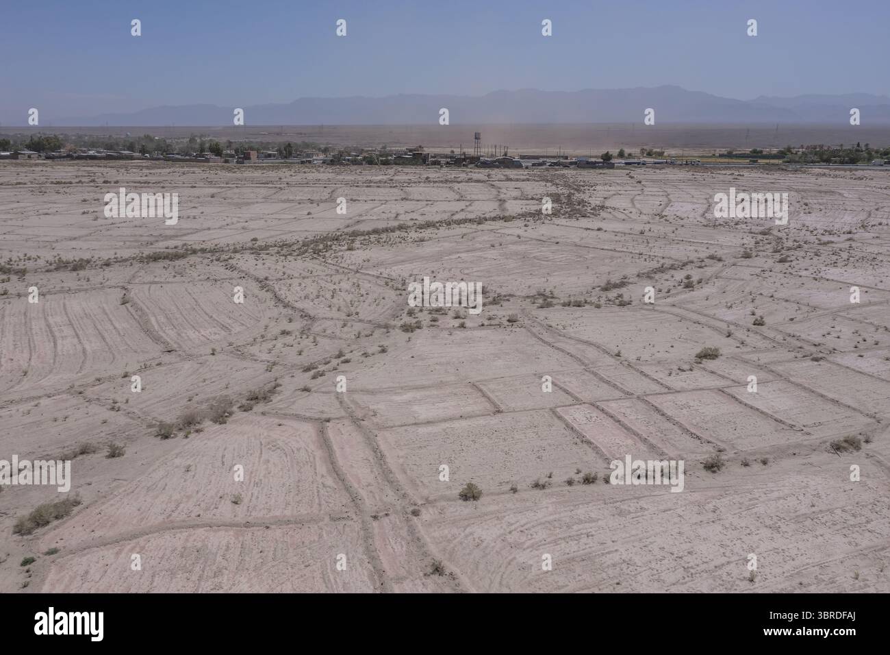 Vue aérienne de la terre desséchée modelée de parcelles agricoles sous un ciel brumeux, le contour faible d'une ville lointaine visible à l'horizon, Bam, Kerm Banque D'Images