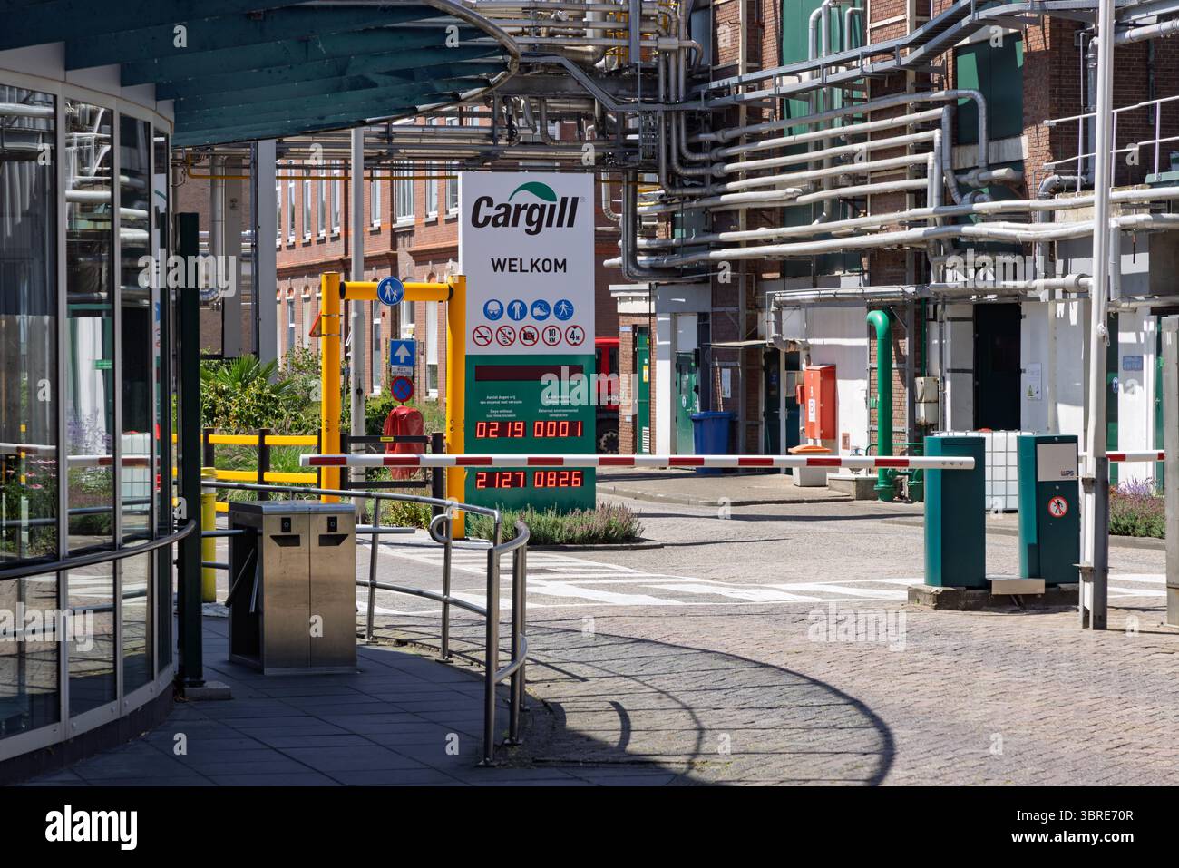 Entrée d'une grande installation industrielle, avec un panneau « Cargill », des barrières et une tuyauterie complexe sous un ciel lumineux. Gouda, pays-Bas, 29 juin 2025 Banque D'Images
