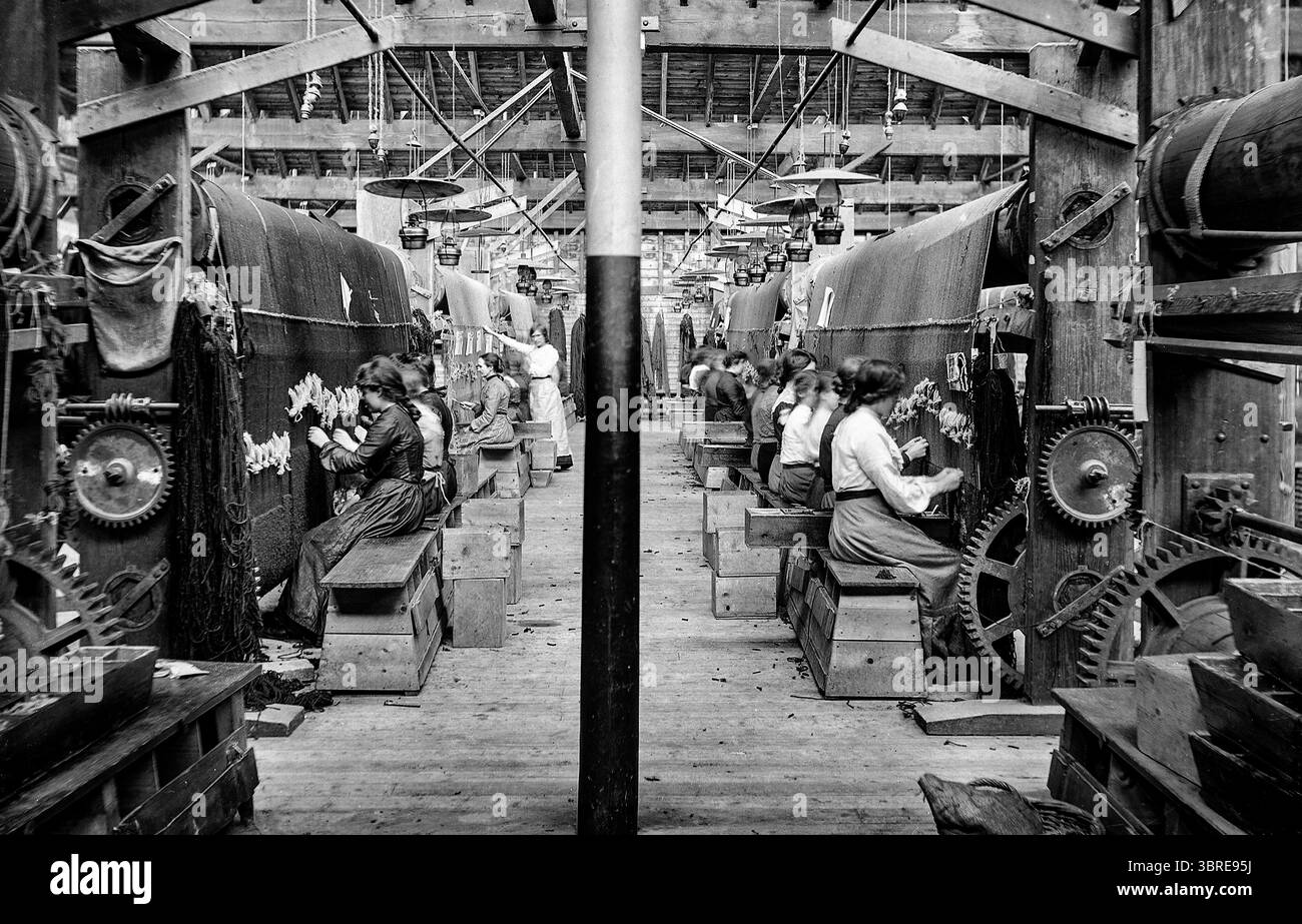 Au début du XXe siècle, les femmes tuffent des tapis dans une usine de Killybegs dans le comté de Donegal, en Irlande. Donegal Carpets a été fondée en 1898 par le fabricant écossais de textile Alexander Morton qui a établi une maison d'artisanat de tapis sur la côte ouest de l'Irlande et a mis en pratique les techniques du peuple Donegal qui travaillait avec la laine depuis des générations. Banque D'Images