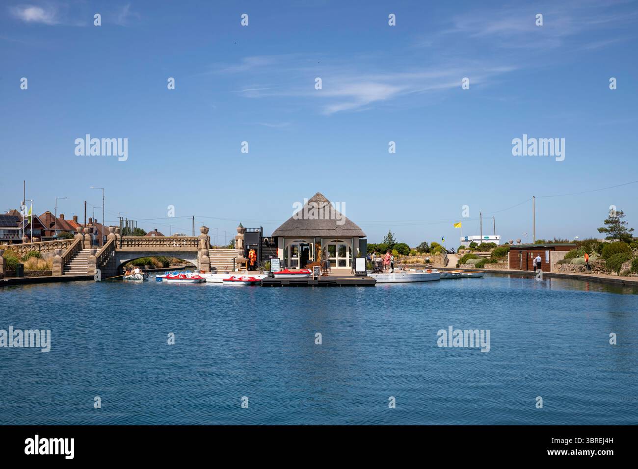 Le café-restaurant au toit de chaume et le pont au centre du lac nautique près du front de mer de Great Yarmouth Banque D'Images