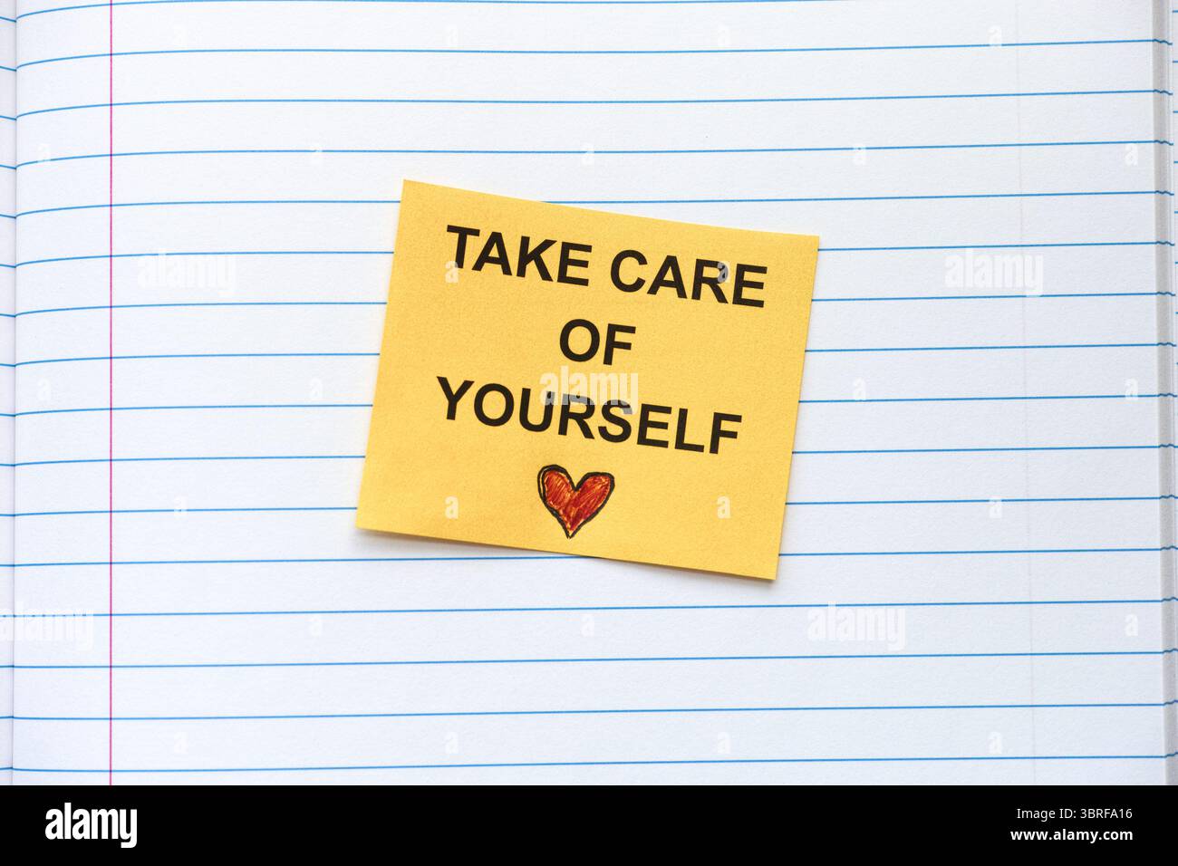 Une note de papier jaune avec les mots prenez soin de vous-même couché sur elle dans un cahier ouvert. Gros plan. Banque D'Images