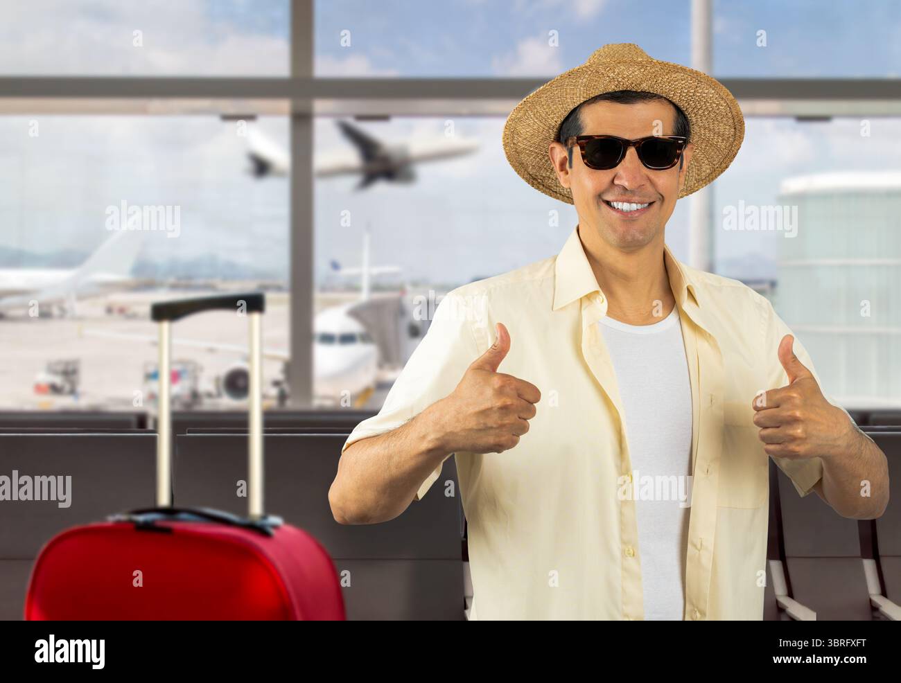 Homme en vacances portant des lunettes de soleil chapeau de chemise jaune à l'aéroport faisant des pouces heureux vers le haut geste avec les mains. Expression d'approbation regardant la caméra wi Banque D'Images