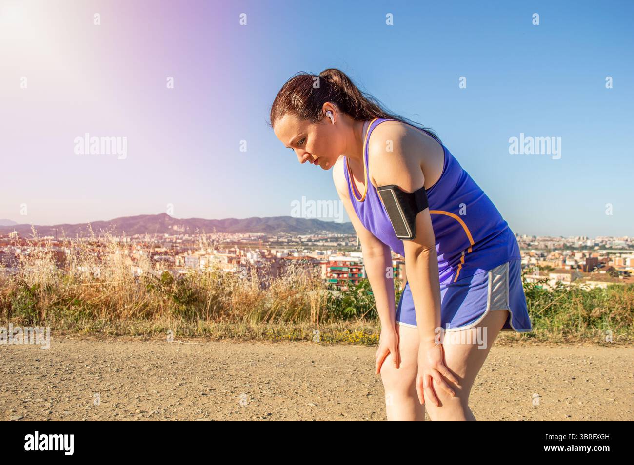 Femme, fatiguée et transpirant de l'exercice en dehors de la ville, fatigue ou épuisement des épreuves du soleil et de la chaleur. Exercice acharné, épuisé Banque D'Images