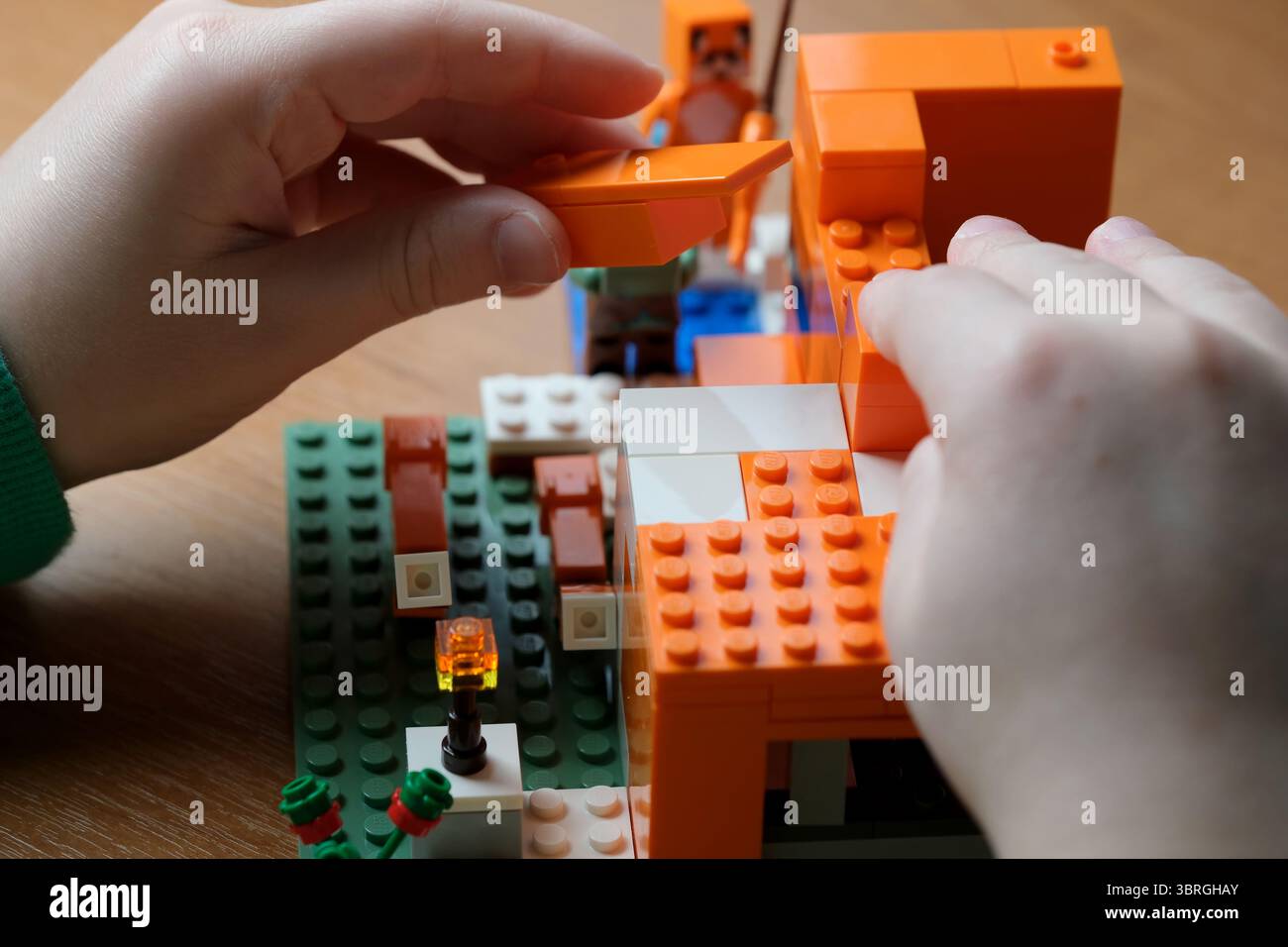 Les mains arrangent habilement des blocs lumineux pendant le temps de construction imaginatif. Banque D'Images