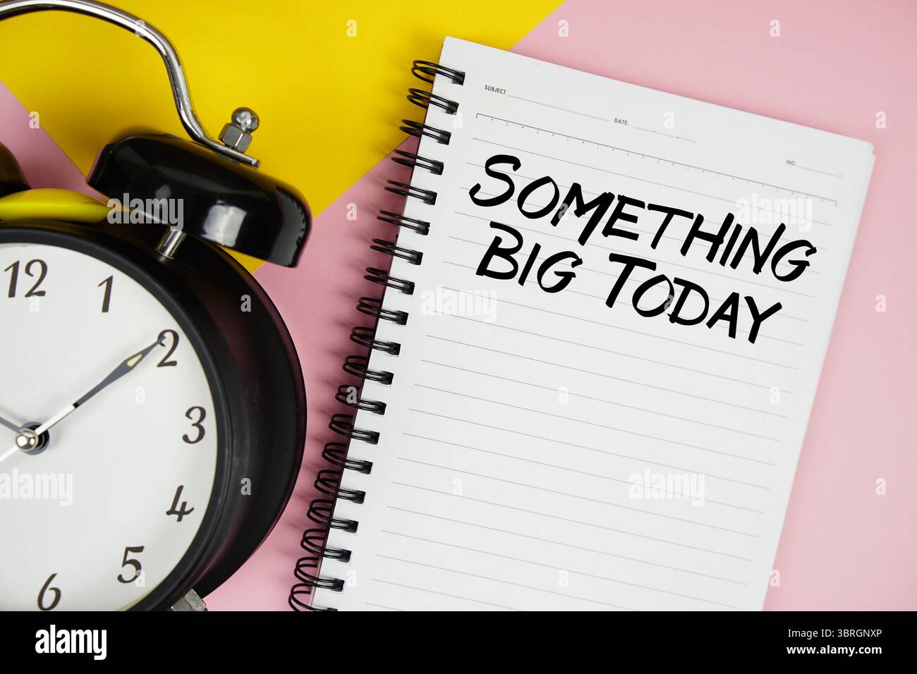 Something Big Today texte écrit sur bloc-notes avec réveil sur fond rose Banque D'Images