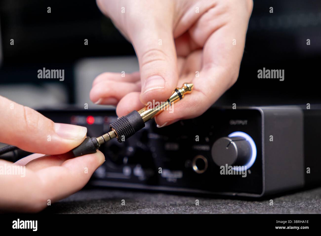 Gros plan détaillé montrant les mains branchant un adaptateur jack audio doré, une étape importante pour la configuration de systèmes audio professionnels pour la production Banque D'Images
