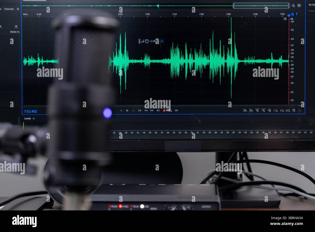 Moniteur d'ordinateur affichant une forme d'onde audio verte détaillée à côté d'un microphone de studio, parfait pour la production audio, les voix off et les médias en ligne Banque D'Images
