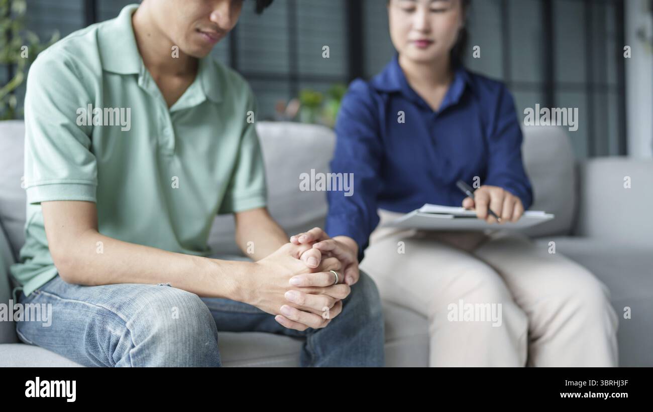 Homme triste assis sur le sofa patient discutant des problèmes de santé mentale avec le psychologue. concept de traitement de la santé mentale de l'homme asiatique déprimé Banque D'Images