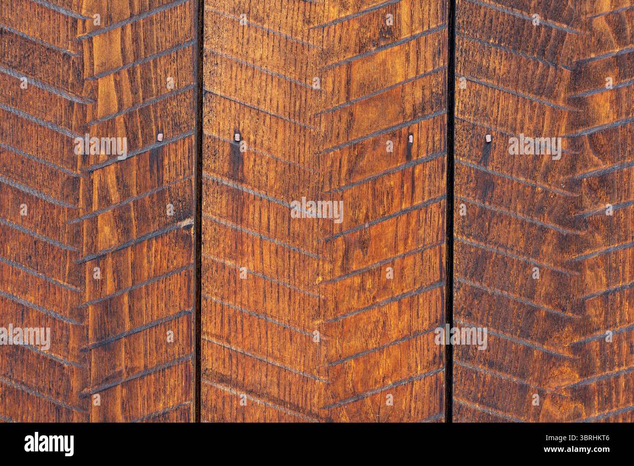 Trois panneaux de bois rustique brun clair avec motif à chevrons incrusté, clous visibles et différentes nuances de grain de bois altéré complexe. Banque D'Images