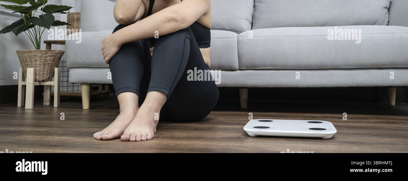 Asiatique femme saine ennuyée de régime perte de poids échouer le régime gras et l'échelle triste femme asiatique bouleversée sur l'échelle de poids à la maison contrôle de poids Banque D'Images