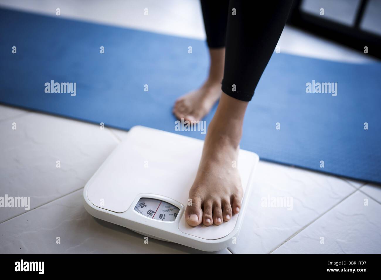 Perdez du poids. Régime gras et pieds de balance debout sur des balances électroniques pour le contrôle du poids. Instrument de mesure en kilogramme pour régime alimentaire Banque D'Images