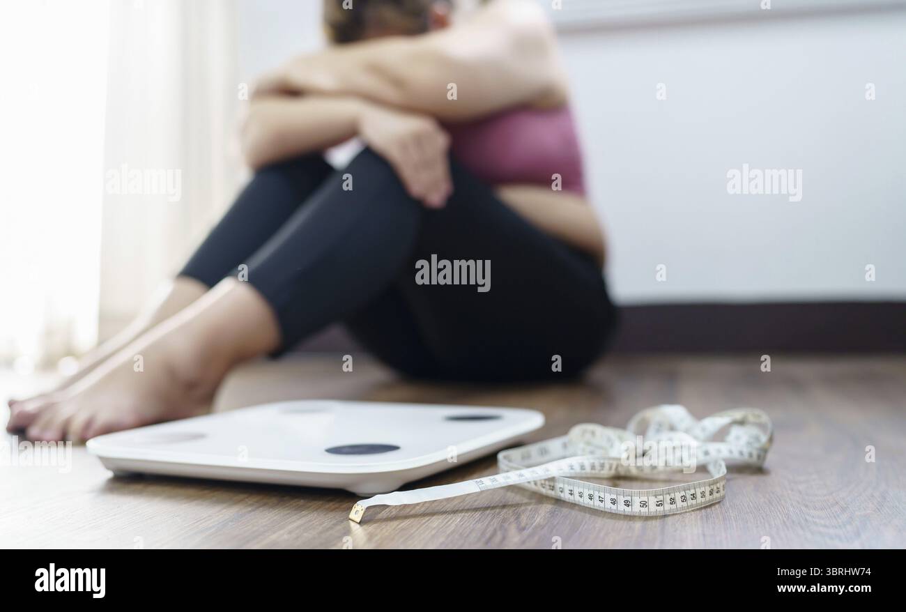 Femme obèse avec le dérangement de graisse ennuyé de régime perte de poids échouer le régime gras et l'échelle triste femme asiatique sur l'échelle de poids à la maison contrôle de poids Banque D'Images