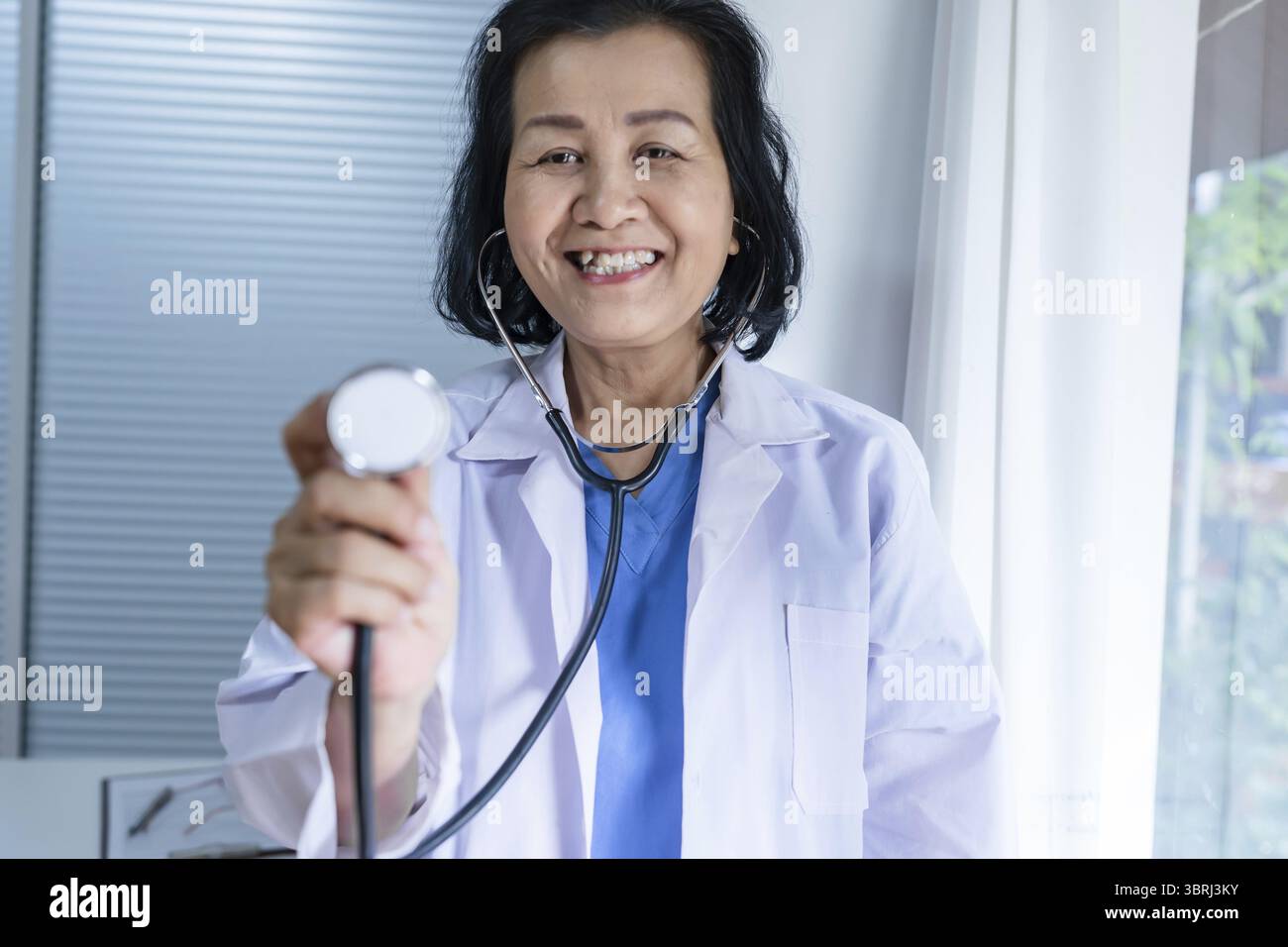 Cardiologue soutient le cœur femme asiatique senior médecin portant des lunettes et uniforme. portrait de vieilles femmes asiatiques matures professionnelles médicales Banque D'Images