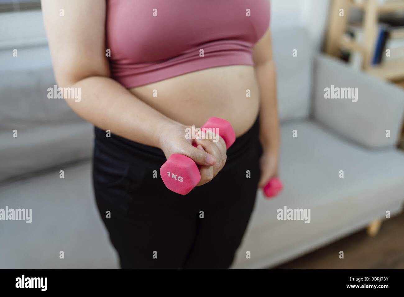 Femme en surpoids exerçant pour perdre du poids. Exercice avec des haltères dans des positions d'étirement à la maison dans le salon joyeux Fat Woman santé diététique Banque D'Images