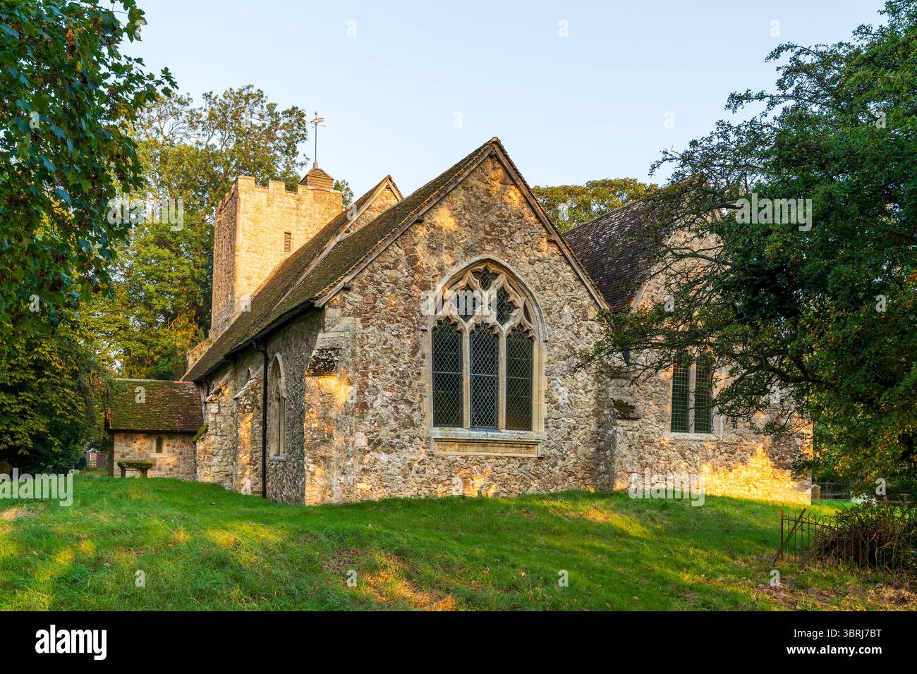 L'église en pierre du 13ème siècle de St Augustine au village Kent de Snave à l'heure dorée tôt le matin. Fenêtres de chœur et tour d'église. Banque D'Images