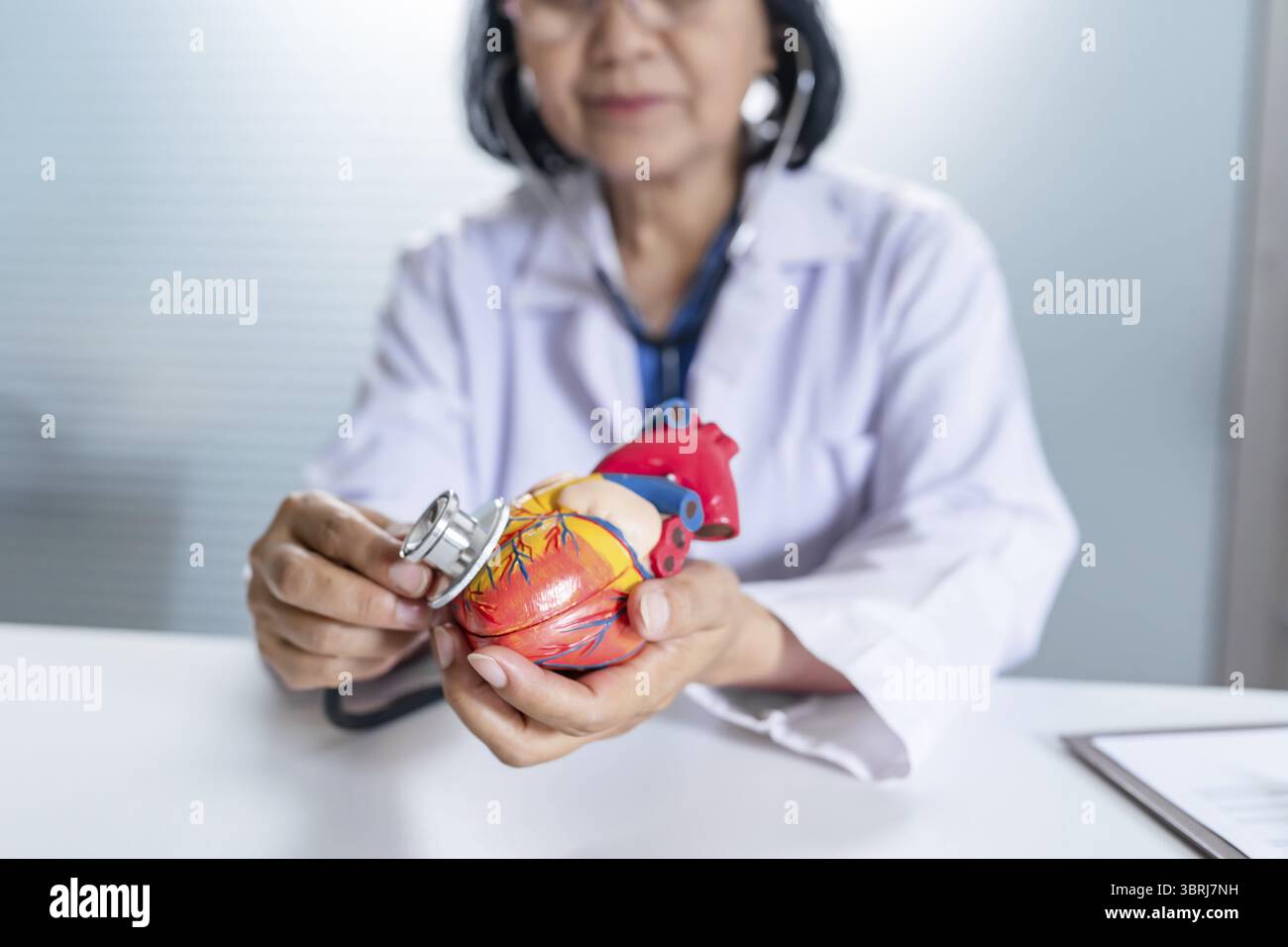 Cardiologue soutient le cœur femme asiatique senior médecin portant des lunettes et uniforme. portrait de vieilles femmes asiatiques matures professionnelles médicales Banque D'Images