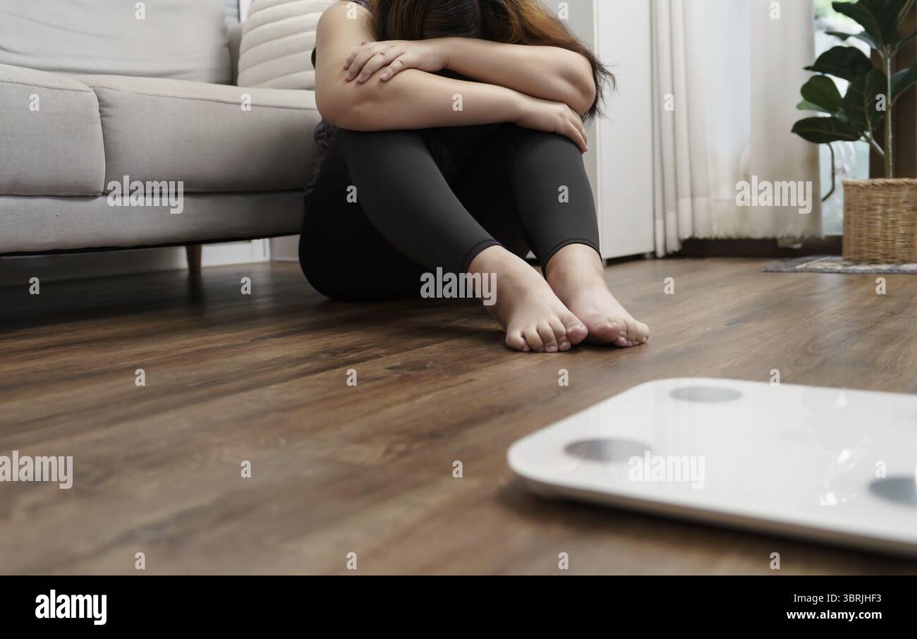 Femme obèse triste avec le dérangement de graisse ennuyé de régime perte de poids échouer le régime de graisse et l'échelle Sad graisse asiatique échelle de poids de femme à la maison contrôle de poids Banque D'Images