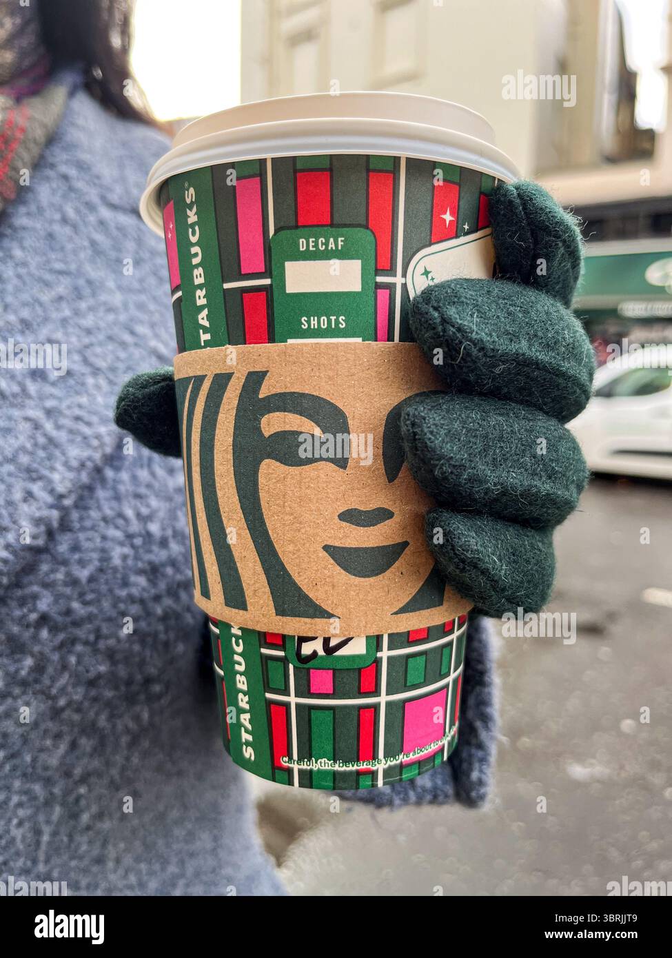 Londres, Royaume-Uni - 28 décembre 2023 : une main gantée tient une tasse de café Starbucks dans une rue glaciale de Londres, mettant en évidence les vibrations hivernales et festives Banque D'Images