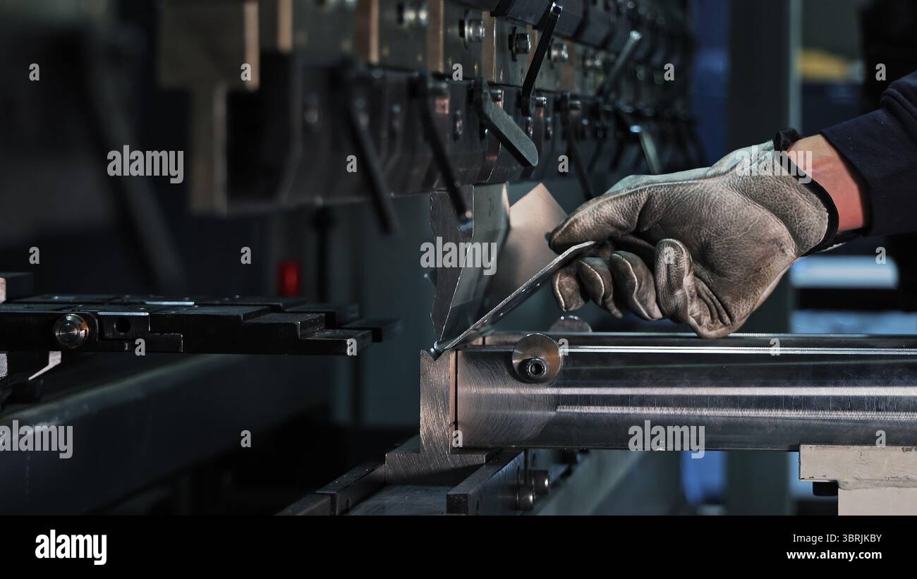 Pliage de tôle sur machine CNC. Ouvrier ganté pliant une tôle métallique à l'aide d'une presse plieuse CNC dans un cadre industriel axé sur la précision Banque D'Images