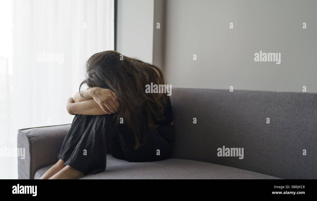 Femme triste pensant à des problèmes assis sur un canapé fille bouleversée se sentant seule et triste de mauvaise relation ou de trouble de la santé mentale de la femme déprimée Banque D'Images
