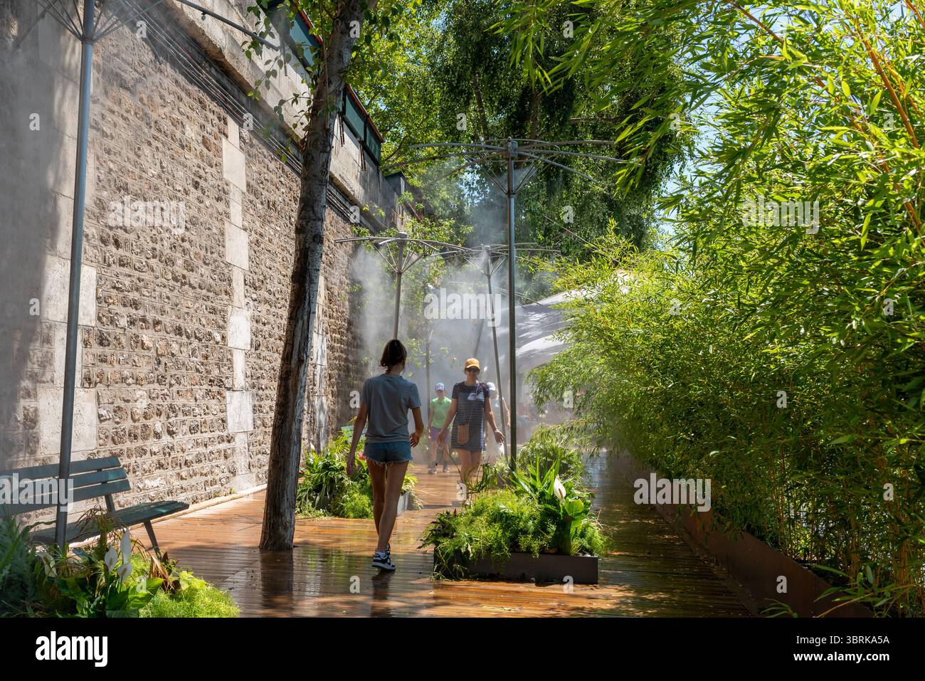Gicleurs d'eau placés sur les berges de la Seine. Les gens essayant de se rafraîchir pendant la chaleur estivale à Paris Banque D'Images