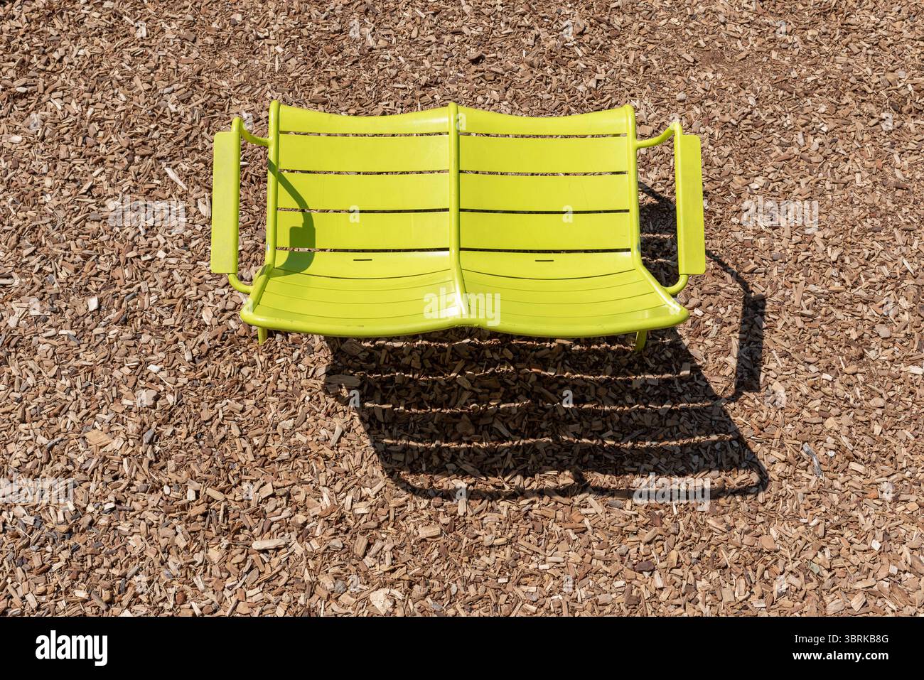 Chaise de jardin double vert citron sur copeaux de bois par une journée ensoleillée. Banque D'Images