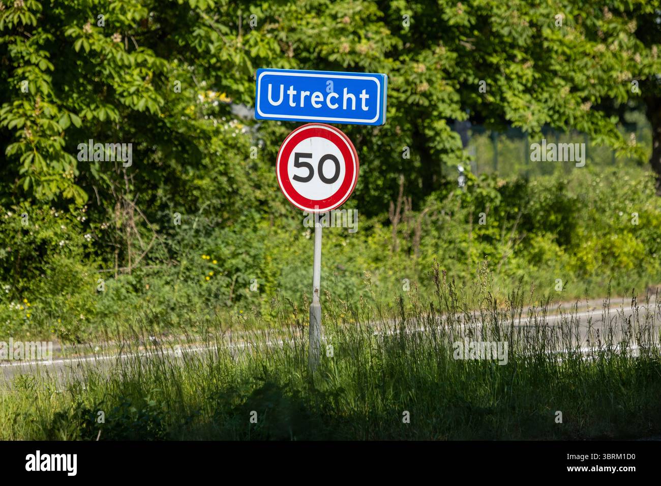 Panneau d'entrée pour Utrecht, pays-Bas, avec un panneau de limitation de vitesse de 50 km h sur une route de campagne, entouré de verdure par une journée ensoleillée. Banque D'Images