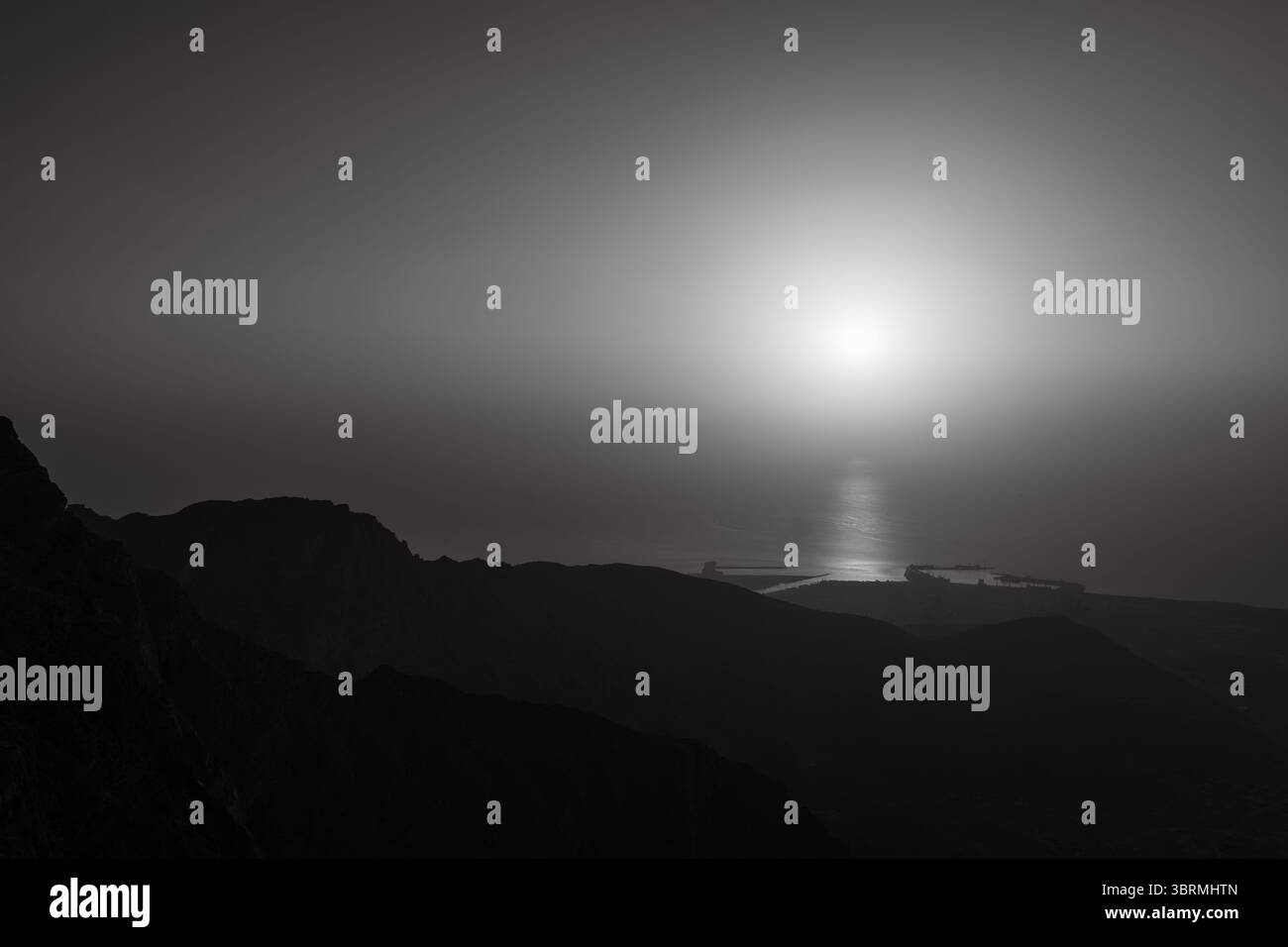 Vue cinématique du coucher de soleil sur les montagnes avec vue sur la mer, silhouette, fond de photographie de nature noir et blanc Banque D'Images