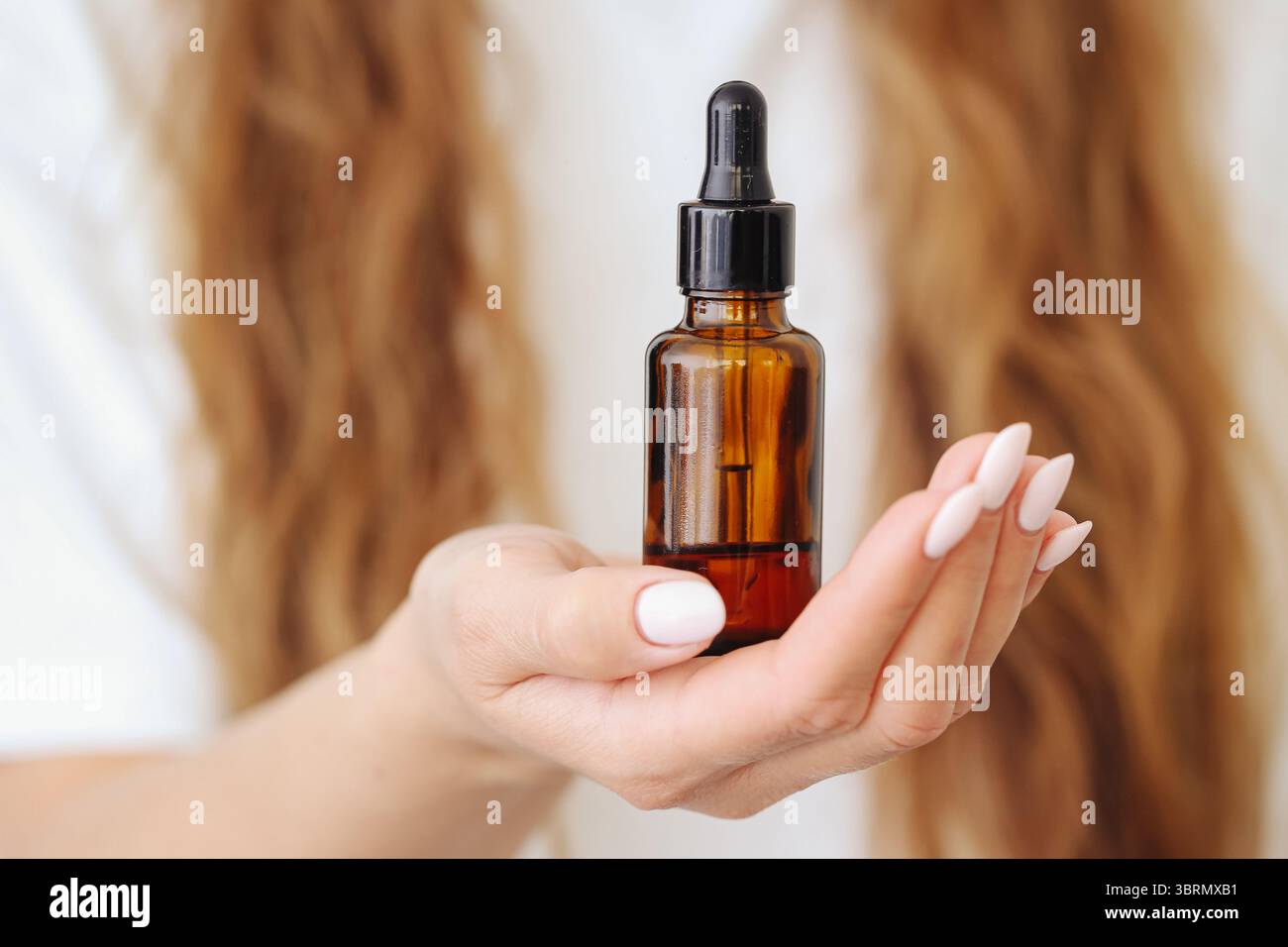 Femme tenant une bouteille d'huile cosmétique. Produit naturel de soin de la peau dans les mains. Compte-gouttes en verre brun avec sérum ou essence. Concept de routine beauté. Banque D'Images