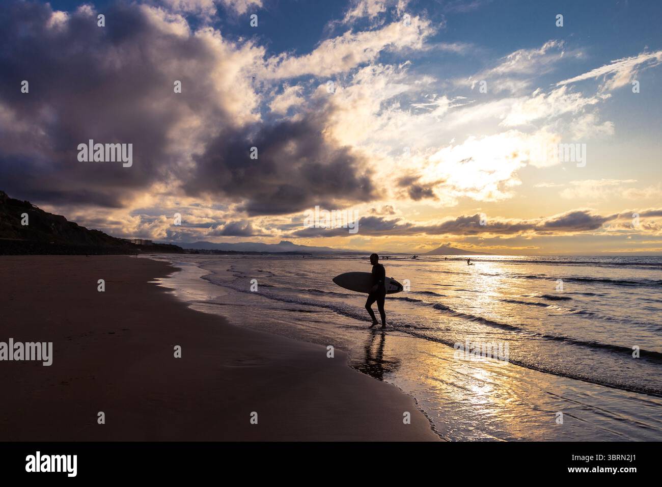 Surfer en descendant la Côte des Basques surf plage au coucher du soleil à Biarritz, France Banque D'Images