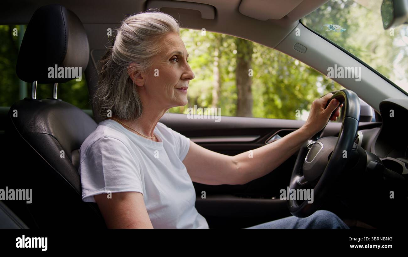 Heureux souriant caucasien mature senior femme propriétaire d'automobile femme grand-mère conducteur d'automobile assis à l'intérieur de la nouvelle voiture électrique moderne Banque D'Images