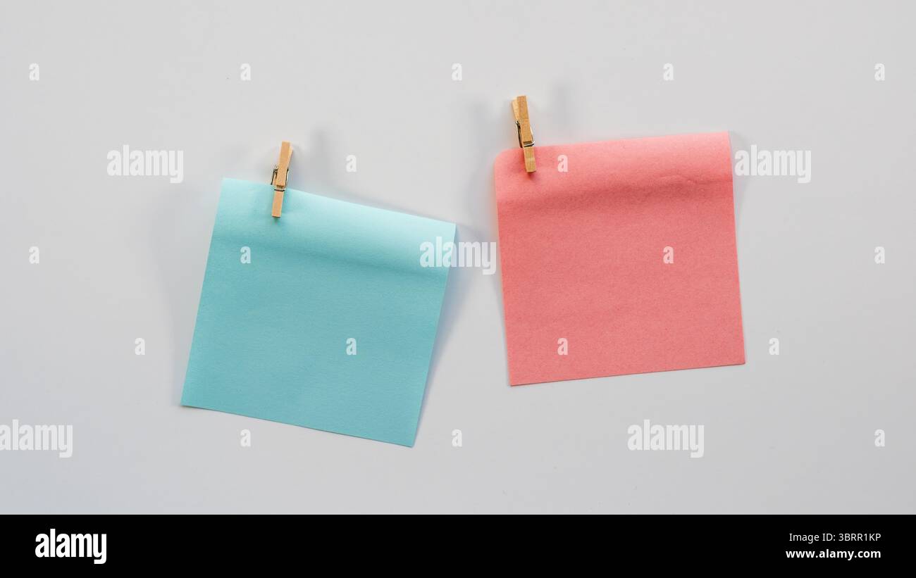 Notes adhésives bleues et roses avec des clips en bois isolés sur fond blanc, le genre garçon OU fille révèlent le fond, le papier peint de décor de douche de bébé Banque D'Images