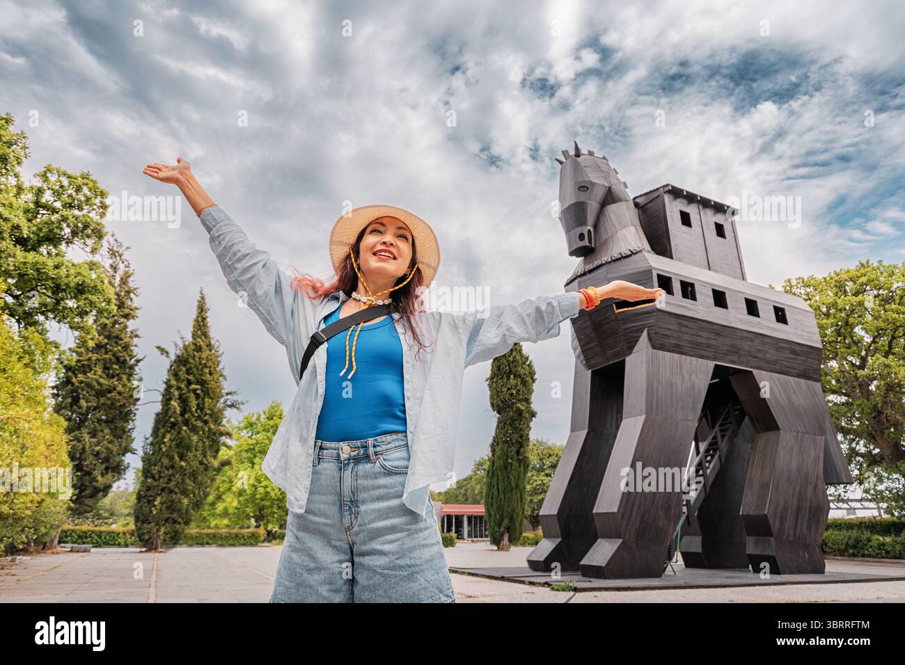 5 mai 2025, Canakkale, Turkiye : touriste levant les armes devant une réplique de cheval de Troie célébrant le voyage et l'histoire en Turquie Banque D'Images