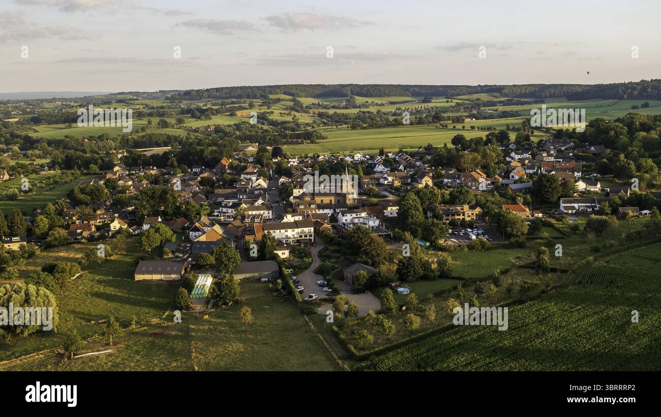 Vue aérienne du village pittoresque niché au milieu de collines verdoyantes et de champs luxuriants, avec un clocher d'église perçant la ligne d'horizon, Epen, Limbourg, pays-Bas. Banque D'Images