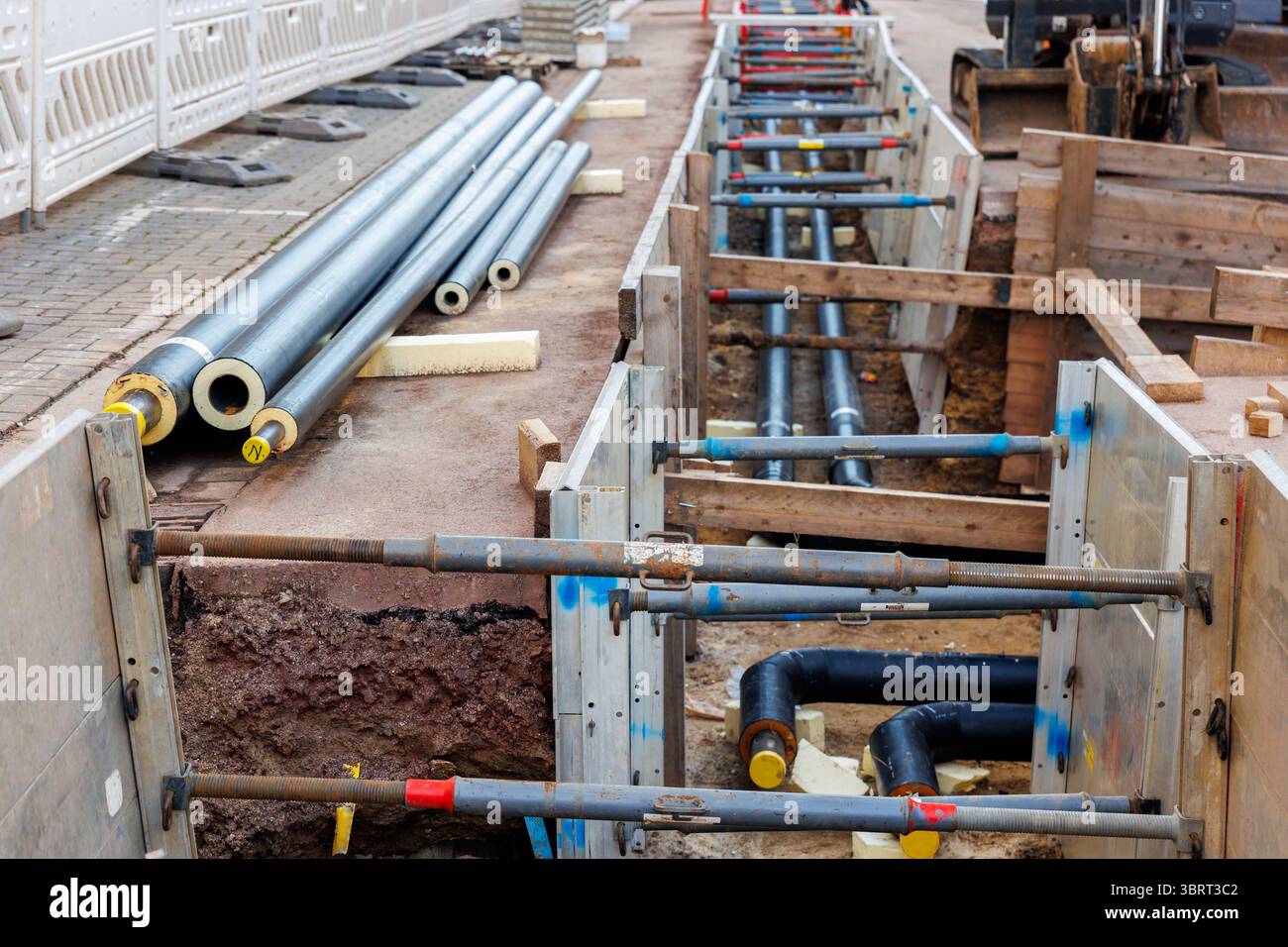 Le nouveau site de construction d'une installation de pipelines urbains isolés modernes a exposé les tuyaux souterrains dans des tranchées étayées. Raccordement de tuyaux en acier isolés Banque D'Images
