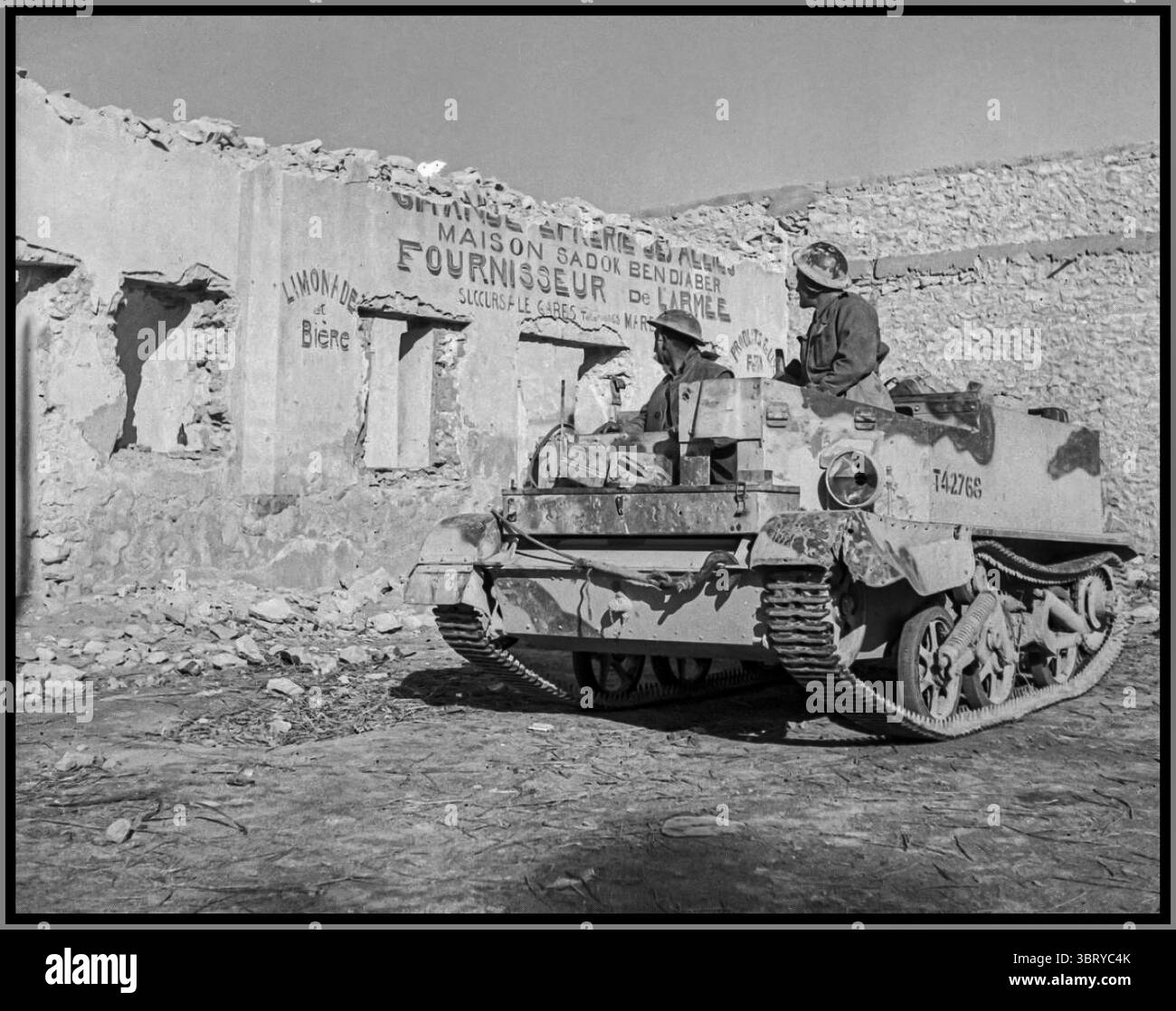 WW2 Afrique du Nord Vickers-Armstrong Bren / Universal Carrier avec des soldats de l'armée britannique passant une armée bombardée de provisions de l'armée magasin Tunisie Afrique du Nord 1940s Banque D'Images WW2 Afrique du Nord Vickers-Armstrong Bren / Universal Carrier avec des soldats de l'armée britannique passant une armée bombardée de provisions de l'armée magasin Tunisie Afrique du Nord 1940s Banque D'Images