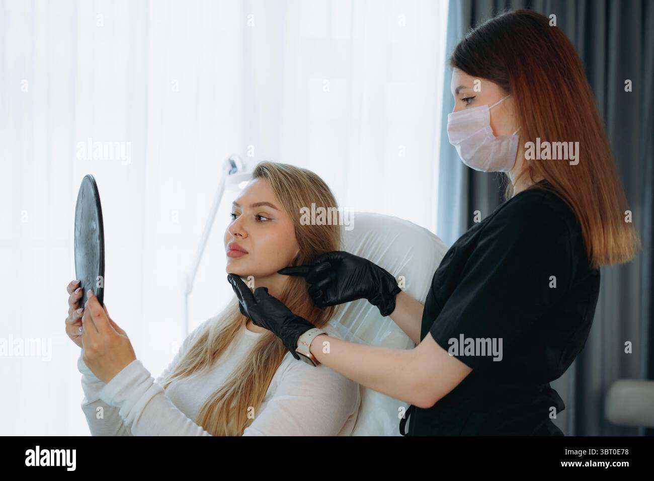 femme regardant dans un miroir après une procédure de rajeunissement facial à la clinique esthétique Banque D'Images