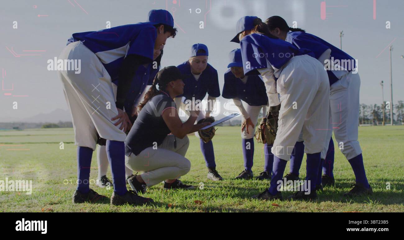 L'équipe de softball se croupissant en écoutant l'entraîneur s'agenouiller avec une planche à pince en extérieur, des maillots bleus, des gants Banque D'Images