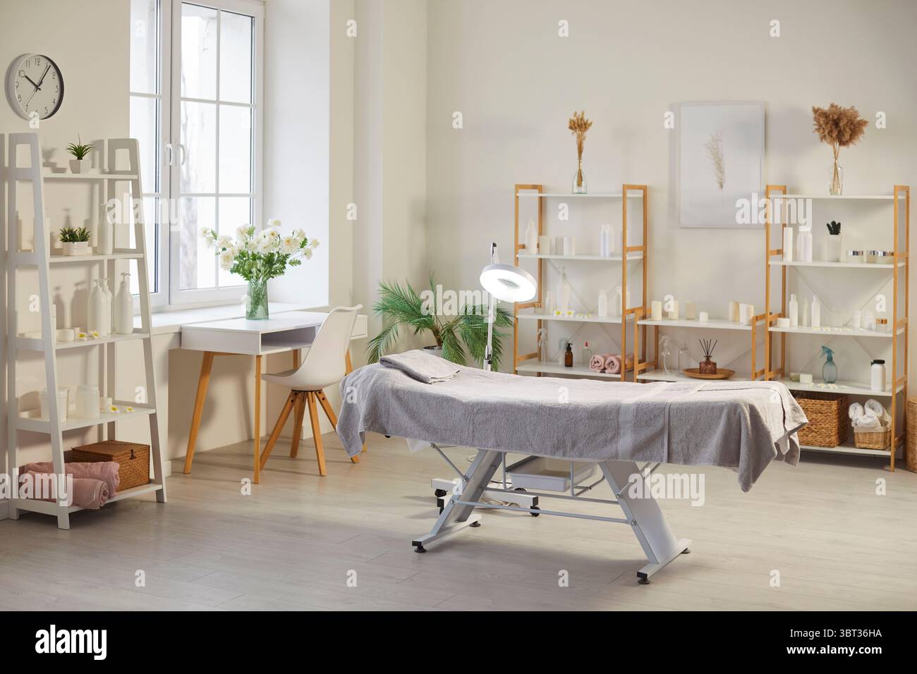 Intérieur de salon de spa vide moderne avec table de massage et étagères remplies de produits de beauté pour la peau. Banque D'Images