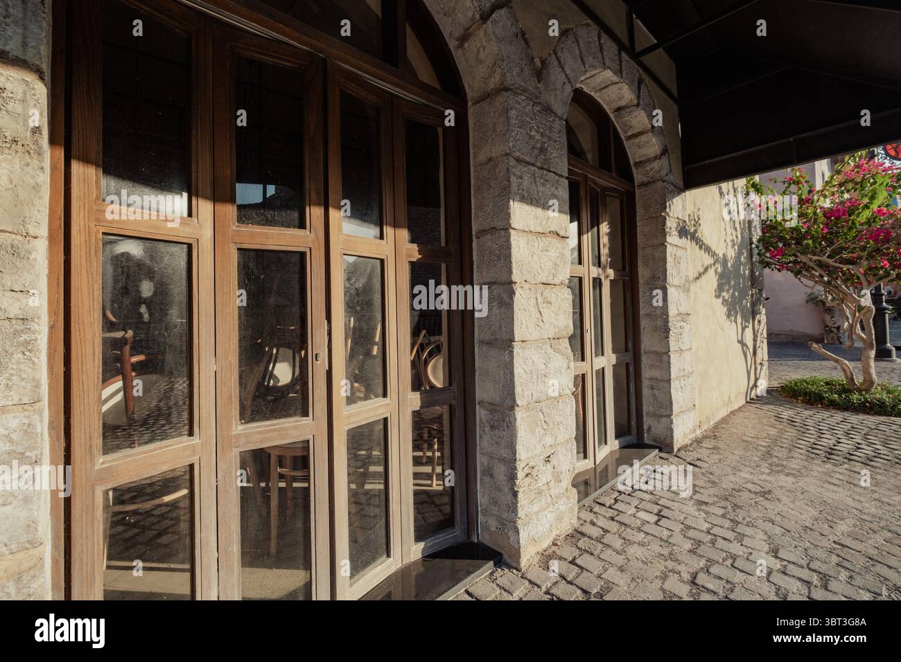 Bâtiment mural en pierre avec fenêtres en bois voûtées et pavé dans un cadre architectural rustique Banque D'Images