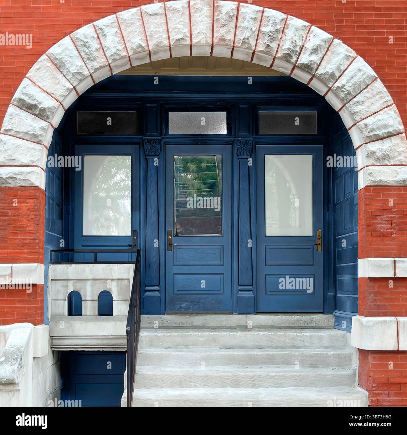 Portes d'entrée bleues triples encadrées par une arche en pierre sur un bâtiment historique de Chicago en briques rouges, avec une garniture classique et un design équilibré et symétrique. Banque D'Images