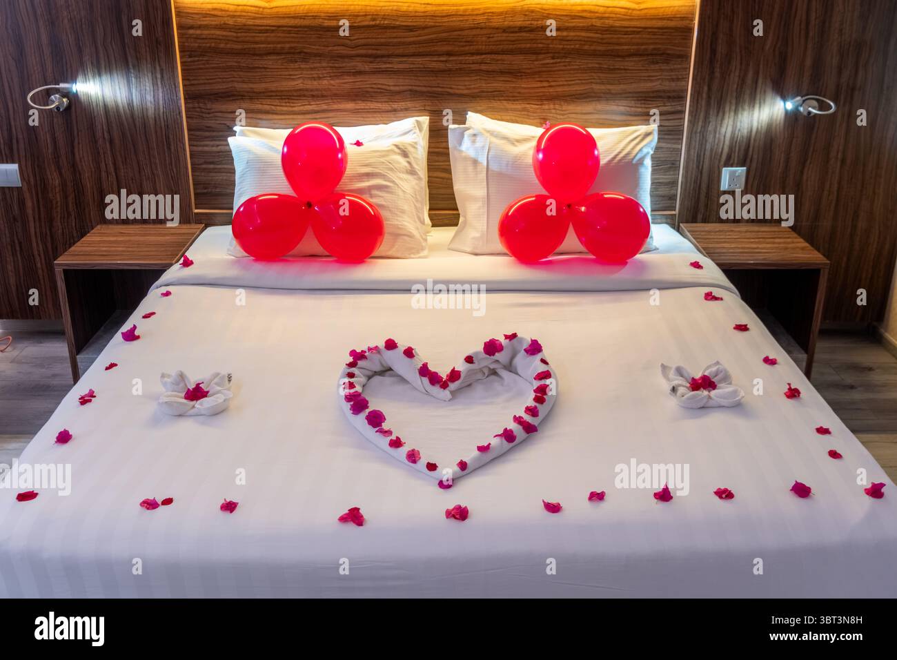 Décor romantique pour la nuit d'anniversaire, pétales de rose et ballons rouges en forme de coeur, décor de suite lune de miel Banque D'Images