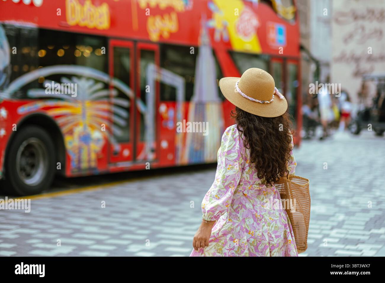 Femme touriste portant une robe fleurie et un chapeau de paille explorant Dubaï dans le bus Hop-on Hop-off Big Red, les sites touristiques et touristiques de Dubaï Banque D'Images