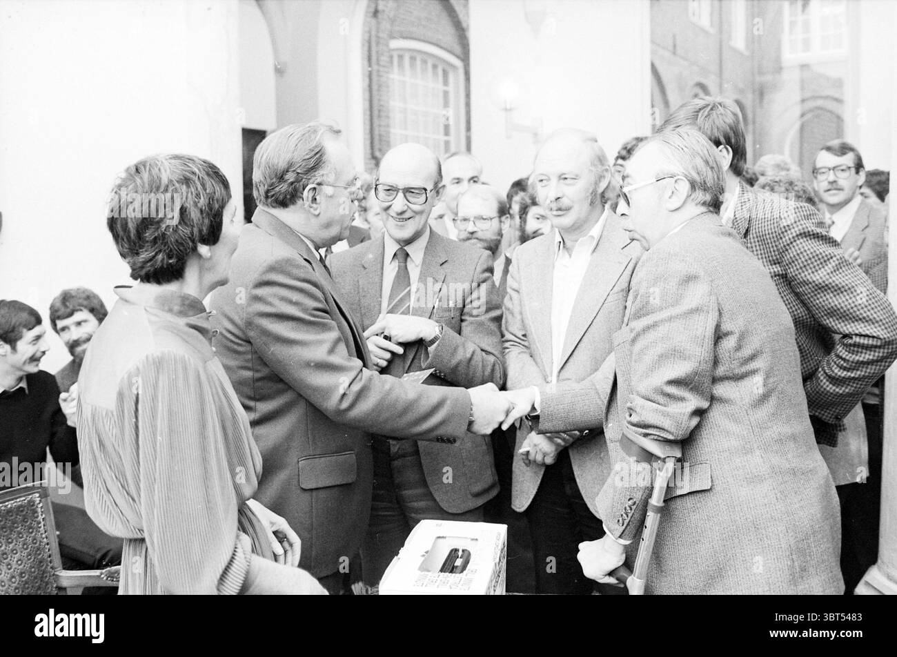 Discours pour le jubilé et réception à la mairie Haarlem Grote Markt pays-Bas, Whizgle News, Dutch Desk, pays-Bas, 1950 - 2000 le 14-11-1981. Ces rubriques apparaissent dans l'image. Dans un cadre intérieur animé, un groupe d'hommes est engagé dans une conversation animée. Au premier plan, trois hommes se serrent la main, leurs expressions de chaleur et de camaraderie. Leurs costumes varient en couleur ; l'un est un fusain profond, tandis qu'un autre apparaît dans un ton plus clair, reflétant un mélange de styles typiques de l'époque. Autour d'eux, d'autres individus se tiennent proches, certains avec des sourires d'approbation Banque D'Images