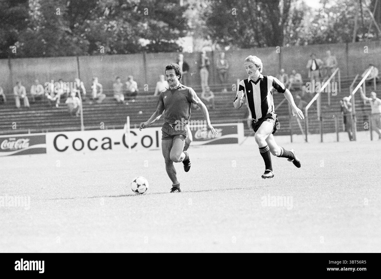 Football HFC Haarlem., Whizgle News, Dutch Desk, pays-Bas, 1950 - 2000. Ce sont les éléments de l'image. Dans un cadre extérieur animé, deux athlètes sont engagés dans un match de football dynamique sur un terrain herbeux. La composition met en évidence le mouvement et l'excitation du jeu. Un joueur, vêtu d'une chemise unie, avance avec détermination, montrant l'intensité de sa concentration. Ses cheveux sont légèrement émoussés, indiquant l'effort physique du jeu. Le pourchasser est un autre joueur, portant une chemise rayée aux couleurs contrastées, incarnant un sentiment d'urgence dans sa stri Banque D'Images