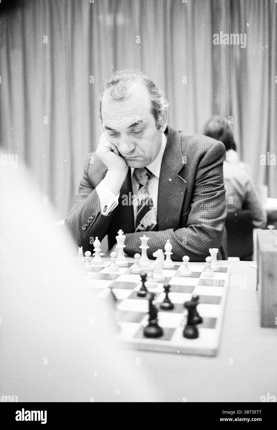 Portraits du groupe de grands maîtres du tournoi d'échecs de Hoogovens (noms voir couverture) tournoi d'échecs de Hoogovens Wijk aan Zee, Whizgle News, Dutch Desk, pays-Bas, 1950 - 2000 le 15-01-1980. Ces rubriques apparaissent dans l'image. Dans un cadre calme et intérieur, la scène est dominée par un échiquier, méticuleusement arrangé avec des pièces au contraste saisissant. L'échiquier est finement détaillé, avec une alternance de carrés sombres et clairs qui mettent en valeur la stratégie en jeu. Un homme est assis intensément à la table, son expression réfléchie et contemplative, suggérant un moment de concentration profonde. Il est le dr. Banque D'Images