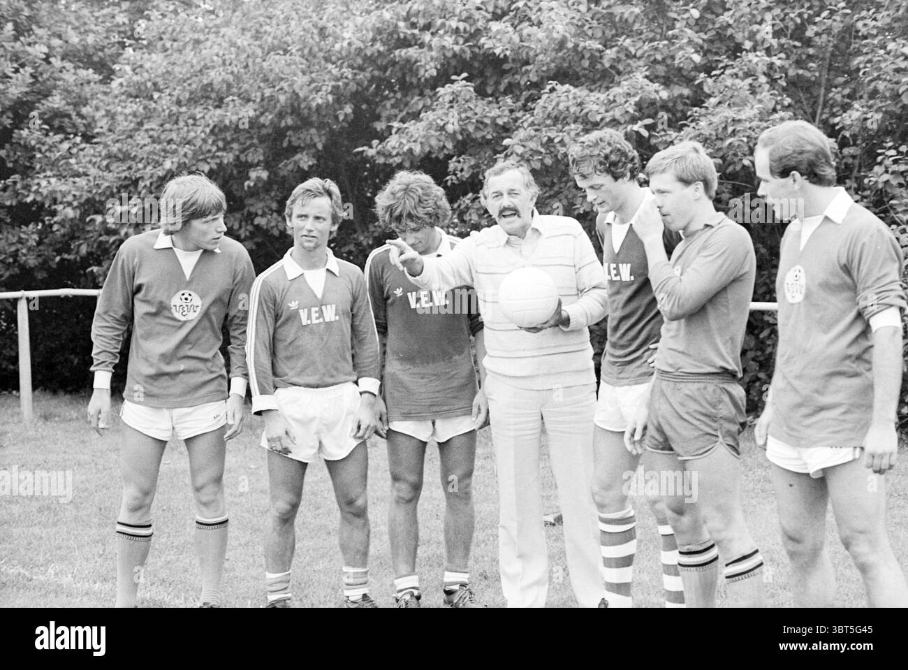 Entraîneur Kuipers VEW + 6 Newcomers Football, Whizgle News, Dutch Desk, pays-Bas, 1950 - 2000 le 16-08-1980. Voici les rubriques de l'image. La scène représente un groupe de six individus debout sur un terrain herbeux, probablement dans un contexte sportif. Les hommes sont habillés dans des maillots athlétiques assortis, principalement avec une nuance de vert profond avec des accents blancs. Chaque maillot présente un logo, ajoutant une touche de branding à leurs tenues. Leurs shorts sont blancs, contrastant avec les hauts plus foncés et révélant des chaussettes aux genoux, dont certaines ont des rayures. Visible dans le groupe est une figure dans une lig Banque D'Images