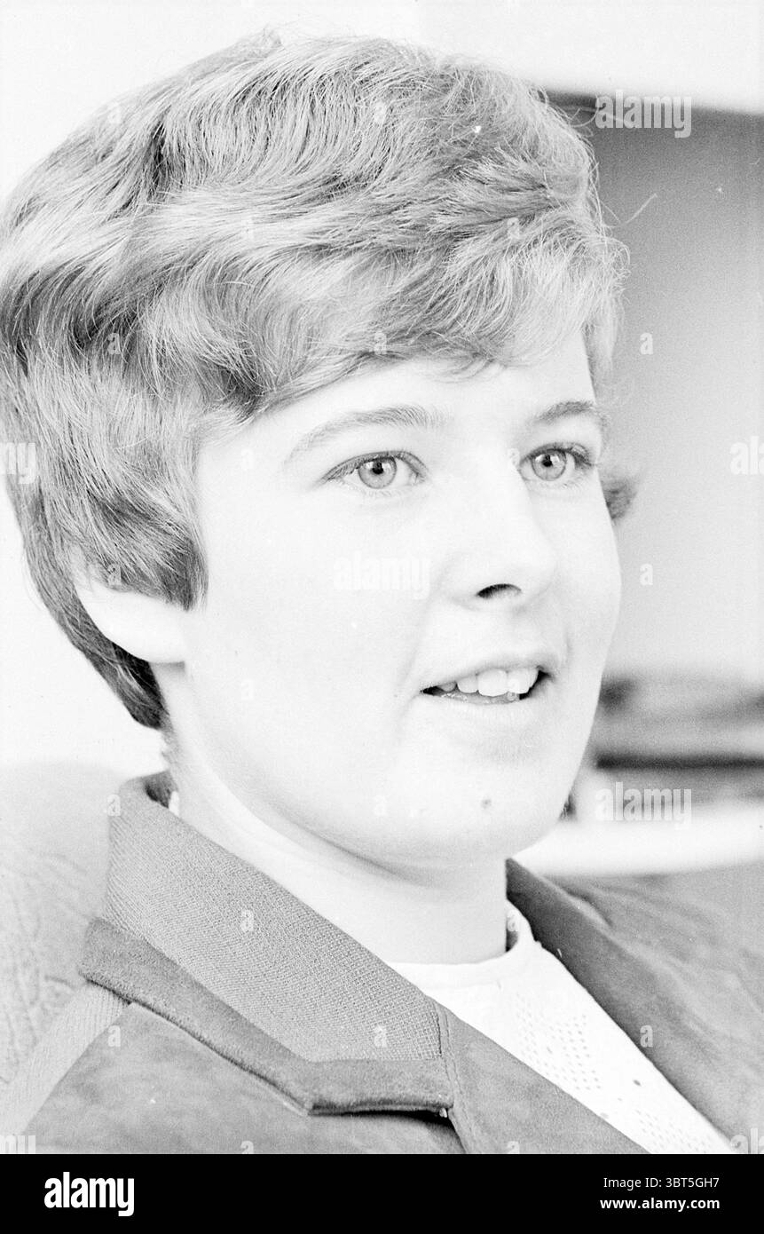 Portrait de E. de Nooijer Portraits, Whizgle News, Dutch Desk, pays-Bas, 1950 - 2000 le 18-04-1967. L'image inclut ces rubriques. Dans cette scène, une jeune femme est capturée en gros plan, avec son visage légèrement éclairé, soulignant ses traits. Elle a des cheveux courts et ondulés qui encadrent son visage, présentant un ton léger et naturel qui ajoute de la chaleur à la composition. Son expression est réfléchie et engageante, avec un léger sourire touchant ses lèvres. L'éclairage est lumineux mais doux, créant une ambiance douce qui met en valeur ses yeux brillants, qui sont un point focal, véhiculant un sentiment d'openne Banque D'Images